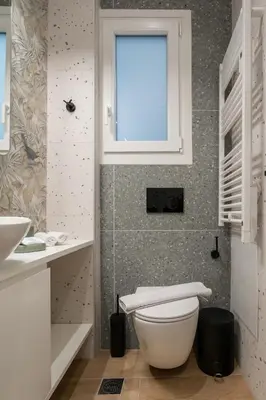 a bathroom with a white toilet and a window at The Minion Elegant Suite Piraeus in Piraeus