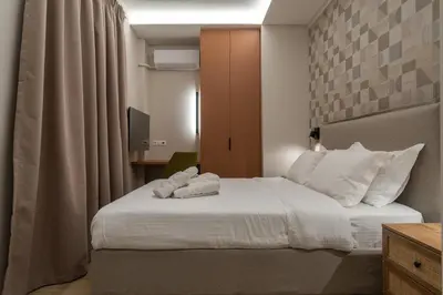 a bedroom with a bed with white sheets and pillows at The Minion Elegant Suite Piraeus in Piraeus