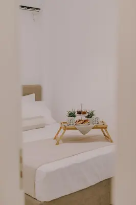 a white bedroom with two beds and a coffee table at Suite Home Nikaia Metro! in Piraeus