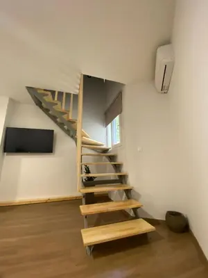 a wooden staircase in a small room with a tv at Living Yard Acropolis Apartments in Athens