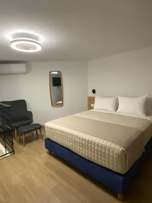 a bedroom with a large bed and a chair at Living Yard Acropolis Apartments in Athens