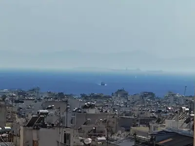 a city with buildings and the ocean in the background at Center Athens all new and fully equipped 2 bedrooms 82 sqm big sea view apt close to Acropoli with Lift in Athens