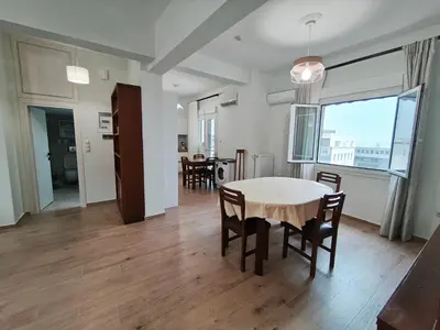 a dining room and living room with a table and chairs at Center Athens all new and fully equipped 2 bedrooms 82 sqm big sea view apt close to Acropoli with Lift in Athens