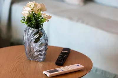 a vase with flowers and a remote control on a table at TheJellyfishDream Sea-view Balcony Piraeus Escape in Piraeus