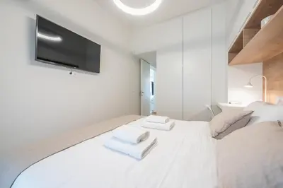 a white bedroom with a large white bed with two towels at Acropolis Luxurious Apartment in Athens