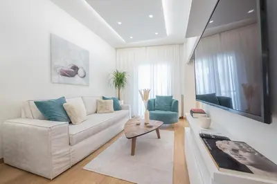 a living room with a white couch and blue chairs at Acropolis Luxurious Apartment in Athens