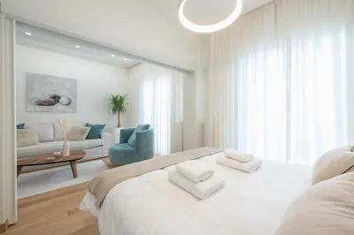 a white bedroom with a large bed and a living room at Acropolis Luxurious Apartment in Athens