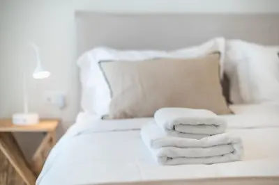 two towels are stacked on a white bed at Acropolis Luxurious Apartment in Athens