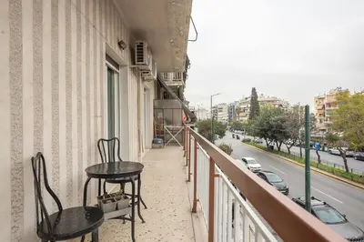 two chairs and a table on a balcony with a street at Athen's cozy home in Athens