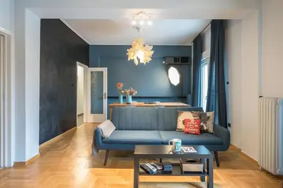 a living room with a blue couch and a table at Athen's cozy home in Athens