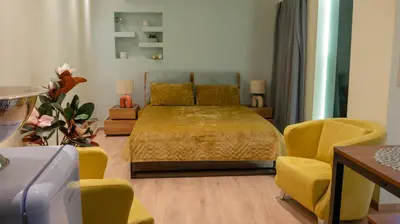 a bedroom with a bed and two yellow chairs at Cozy Roots in Athens
