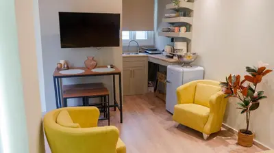 a kitchen with two yellow chairs and a desk with a tv at Cozy Roots in Athens