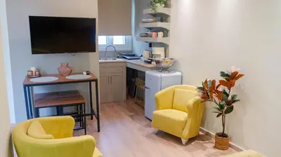 a kitchen with yellow chairs and a table and a counter at Cozy Roots in Athens