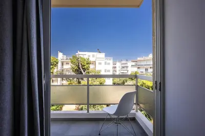 a white chair sitting on a balcony with a window at Varkizaki by the sea in Varkiza
