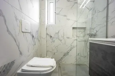 a white bathroom with a toilet and a shower at Varkizaki by the sea in Varkiza