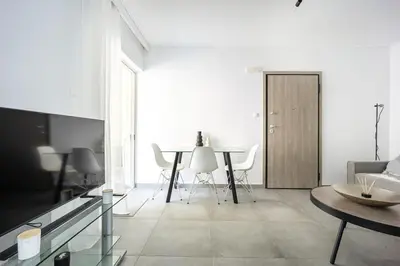 a white living room with a table and chairs at Varkizaki by the sea in Varkiza