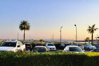 a group of cars parked in a parking lot with palm trees at Beachside Retreat in Glyfada in Athens