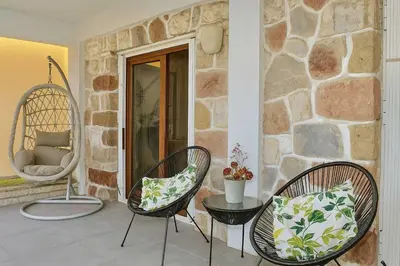 a patio with two chairs and a table and a stone wall at Beachside Retreat in Glyfada in Athens