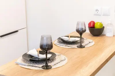 two wine glasses and plates on a wooden counter at Little Paradise in Athens with a Church View in Athens