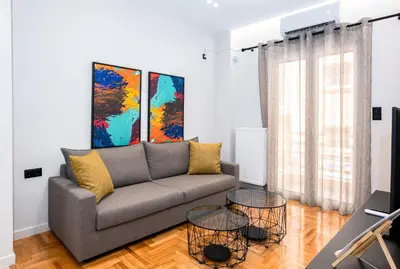 a living room with a couch and two paintings at Stylish 2BR flat near hospital & Panormou metro in Athens