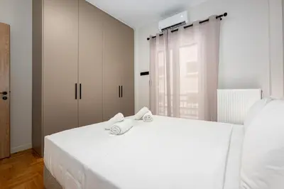 a bedroom with a white bed with towels on it at Stylish 2BR flat near hospital & Panormou metro in Athens