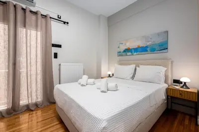 a white bedroom with a large white bed with white pillows at Stylish 2BR flat near hospital & Panormou metro in Athens
