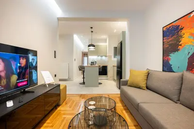 a living room with a couch and a flat screen tv at Stylish 2BR flat near hospital & Panormou metro in Athens