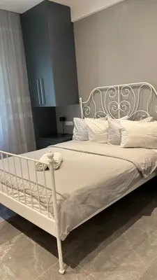 a white bed with a metal headboard and white pillows at Agios Nikolaos apartment in Athens
