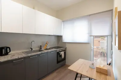 a kitchen with white cabinets and a wooden table at Spacious Luxury Apartment Near Piraeus Port in Piraeus