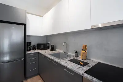 a kitchen with white cabinets and a stainless steel refrigerator at Spacious Luxury Apartment Near Piraeus Port in Piraeus