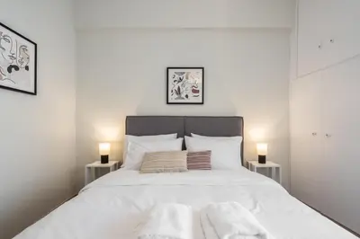 a white bedroom with a large white bed with two lamps at Spacious Luxury Apartment Near Piraeus Port in Piraeus