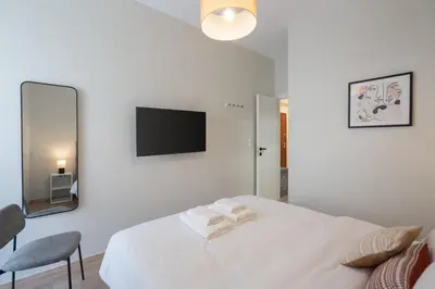 a white bedroom with a bed and a tv at Spacious Luxury Apartment Near Piraeus Port in Piraeus