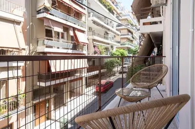a balcony with two chairs and a view of a building at Spacious Luxury Apartment Near Piraeus Port in Piraeus