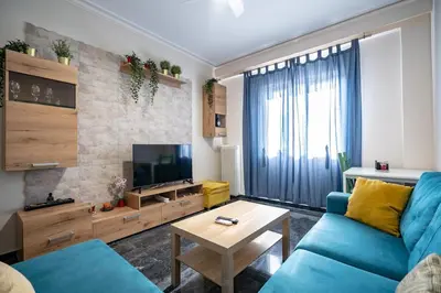 a living room with a blue couch and a television at Athens Vibe Apartment - Gazi by ΜΡS in Athens