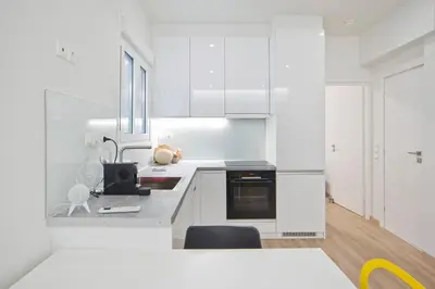 a white kitchen with white cabinets and a table at Aether Athens Luxurious Fully Renovated Apt in Athens