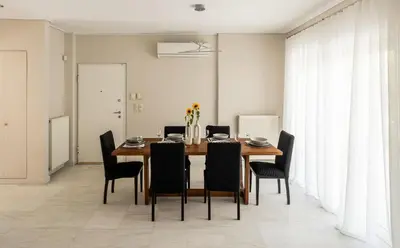 a dining room with a wooden table and black chairs at Elegant 3BD Seaside Villa With Sea View In Vari in Vari