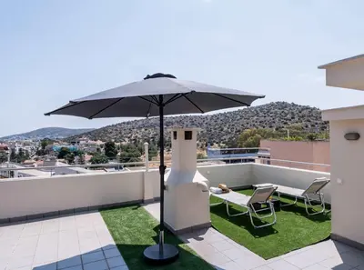 a patio with an umbrella and chairs on a roof at Elegant 3BD Seaside Villa With Sea View In Vari in Vari