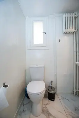 a white bathroom with a toilet and a window at Athens Central Jacuzzi Retreat in Athens