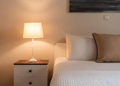 a lamp on a night stand next to a bed at Relax & Comfy 2BR Apt Close To Athens Center in Athens