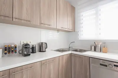a white kitchen with wooden cabinets and a sink at Cozy Athens 2bdr Apartment in Athens