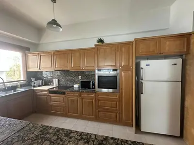 a kitchen with wooden cabinets and a white refrigerator at AthensView Skyline High-rise with Acropolis view -TWO BEDROOM FLAT in Athens