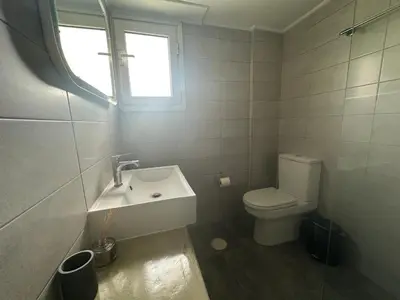 a bathroom with a toilet and a sink and a window at AthensView Skyline High-rise with Acropolis view -TWO BEDROOM FLAT in Athens