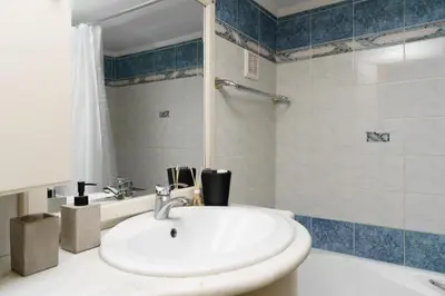 a bathroom with a white sink and a shower at Adigonis Apartment next to the metro station in Athens