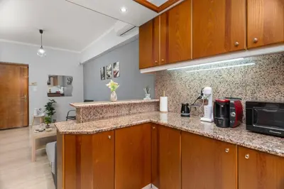 a kitchen with wooden cabinets and a counter top at Adigonis Apartment next to the metro station in Athens