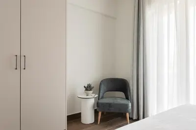 a chair in a bedroom next to a window at KLEO by Zoia Living in Athens