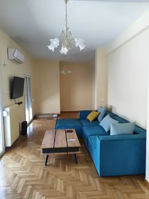 a living room with a blue couch and a table at Comfortable penthouse in Kallithea in Athens