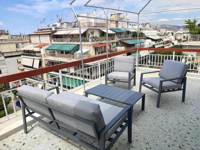 two chairs and a table on a balcony with buildings at Comfortable penthouse in Kallithea in Athens