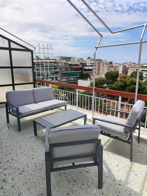 a patio with two chairs and a table on a roof at Comfortable penthouse in Kallithea in Athens