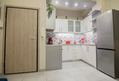 a kitchen with white cabinets and a refrigerator at Urban Ceramic Apartment by GHH in Athens