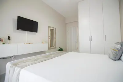 a white bedroom with a bed and a flat screen tv at Urban Ceramic Apartment by GHH in Athens
